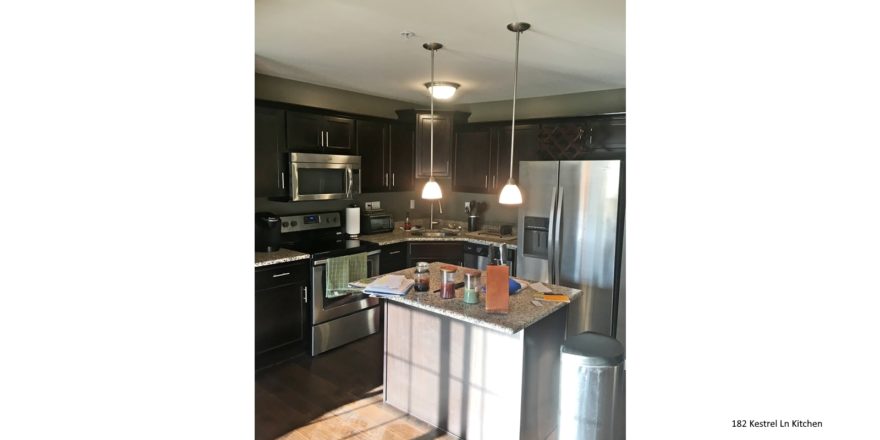 Kitchen with wood-style floor, stainless steel appliances, dark wood cabinets, and island