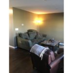 Living room with wood-style flooring, accent rug, coffee table, leather arm chair, and couch with pillows