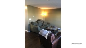 Living room with wood-style flooring, accent rug, coffee table, leather arm chair, and couch with pillows