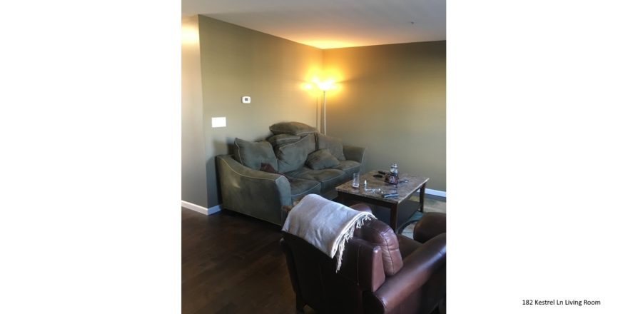 Living room with wood-style flooring, accent rug, coffee table, leather arm chair, and couch with pillows