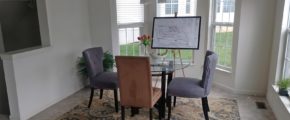 Dining room with tile flooring, accent rug, glass table with chairs, and large bay window