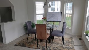 Dining room with tile flooring, accent rug, glass table with chairs, and large bay window