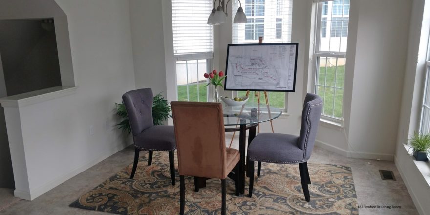 Dining room with tile flooring, accent rug, glass table with chairs, and large bay window