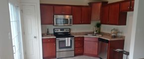 Kitchen with stainless steel appliances, tile floor, cherry wood cabinets and marble-style countertops