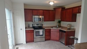 Kitchen with stainless steel appliances, tile floor, cherry wood cabinets and marble-style countertops