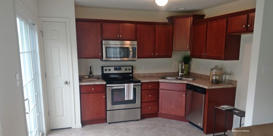 Kitchen with stainless steel appliances, tile floor, cherry wood cabinets and marble-style countertops