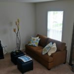 Living room with love seat, window, large mirror, two small accent tables, and decor
