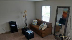 Living room with love seat, window, large mirror, two small accent tables, and decor