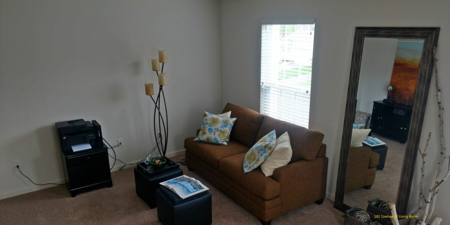 Living room with love seat, window, large mirror, two small accent tables, and decor