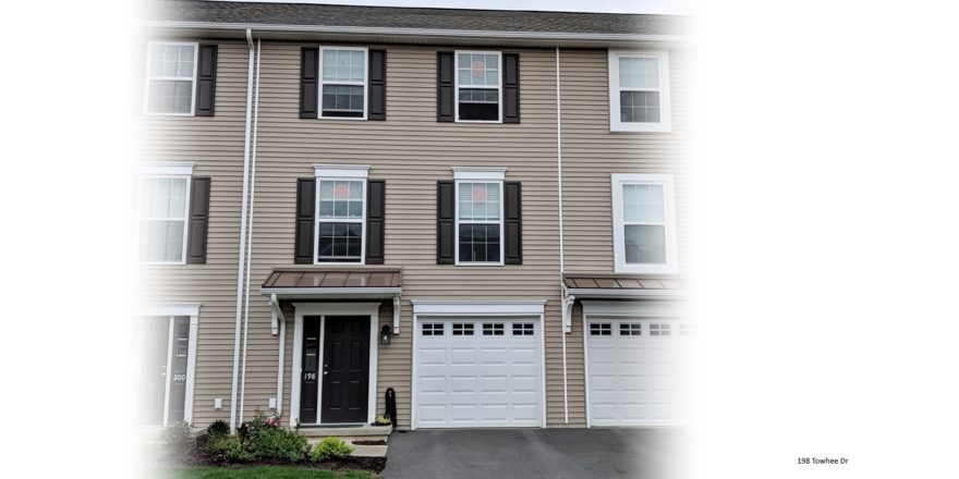 Exterior of townhouse with tan siding and dark brown shutters and front door