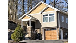 Craftsmen style house with stone siding, tan siding, and cedar shake shingle siding