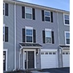 Exterior of townhome with gray siding and black shutters and front door