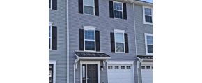 Exterior of townhome with gray siding and black shutters and front door