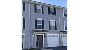 Exterior of townhome with gray siding and black shutters and front door