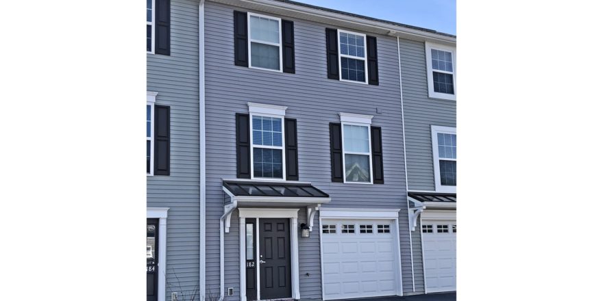 Exterior of townhome with gray siding and black shutters and front door