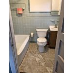 Bathroom with tub, toilet, vanity, medicine cabinet. Wall is blue tile