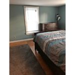 Bedroom with full bed, throw rug, wood dresser with four drawers, and a large window