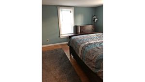 Bedroom with full bed, throw rug, wood dresser with four drawers, and a large window