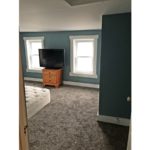 Bedroom with queen bed, dresser, and TV