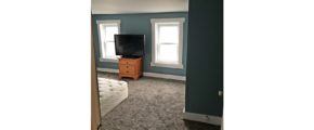 Bedroom with queen bed, dresser, and TV