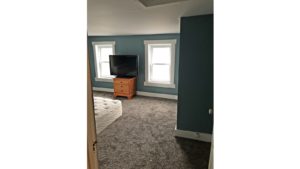 Bedroom with queen bed, dresser, and TV