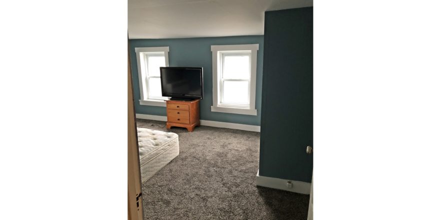 Bedroom with queen bed, dresser, and TV