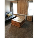Den with leatherette futon and wooden chest coffee table