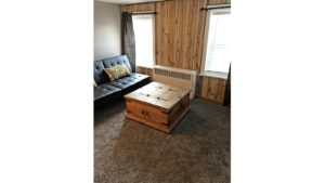 Den with leatherette futon and wooden chest coffee table