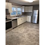 Kitchen with large tile floor, stainless steel appliances, and white cabinets.