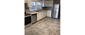 Kitchen with large tile floor, stainless steel appliances, and white cabinets.