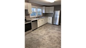 Kitchen with large tile floor, stainless steel appliances, and white cabinets.