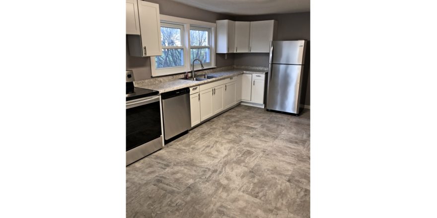 Kitchen with large tile floor, stainless steel appliances, and white cabinets.