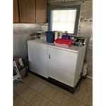 Laundry room with side-by-side top load washer and front load dryer with cabinets perpendicularly above.