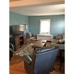 Living room with coffee table, two leatherette recliners, suede couch, TV and entertainment center