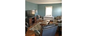 Living room with coffee table, two leatherette recliners, suede couch, TV and entertainment center