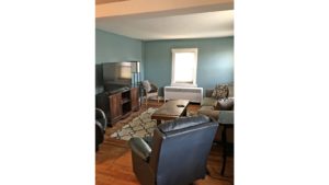 Living room with coffee table, two leatherette recliners, suede couch, TV and entertainment center