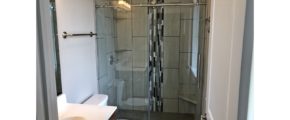 Bathroom with shower stall with frameless glass sliding door, toilet, and vanity with mirror