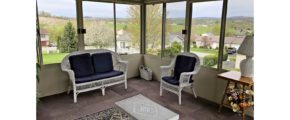 Sunporch with wicker furniture, rug, end table, and large windows