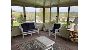 Sunporch with wicker furniture, rug, end table, and large windows