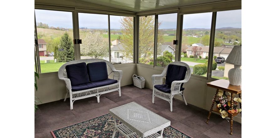 Sunporch with wicker furniture, rug, end table, and large windows