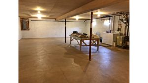 Large, unfinished basement with side-by-side front load washer and top load dryer
