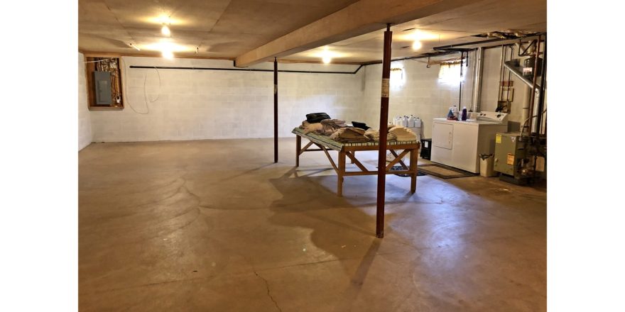 Large, unfinished basement with side-by-side front load washer and top load dryer
