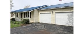Exterior of ranch house with yellow siding and maroon shutters, covered front porch, two car garage, and driveway