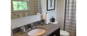 Bathroom with mirror, vanity, toilet, shower stall with curtain and large window