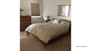Carpeted bedroom with full bed, dresser with six drawers, nightstand, painting, and window