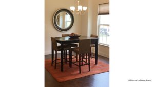 Dining room with square, bar-height dining table, wood-style flooring, accent rug, mirror, and window