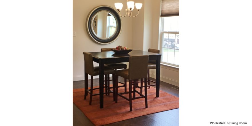Dining room with square, bar-height dining table, wood-style flooring, accent rug, mirror, and window