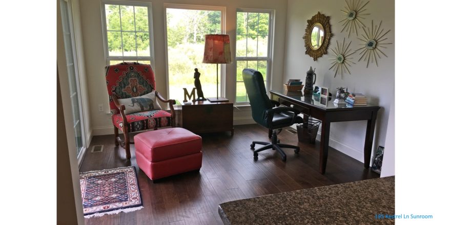 Sunroom with wood-style flooring, chair, desk with chair, mirror and large windows