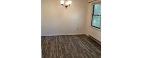 Unfurnished dining room with wood-style flooring and chandelier.