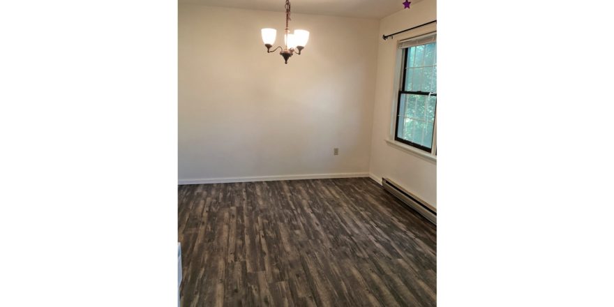 Unfurnished dining room with wood-style flooring and chandelier.